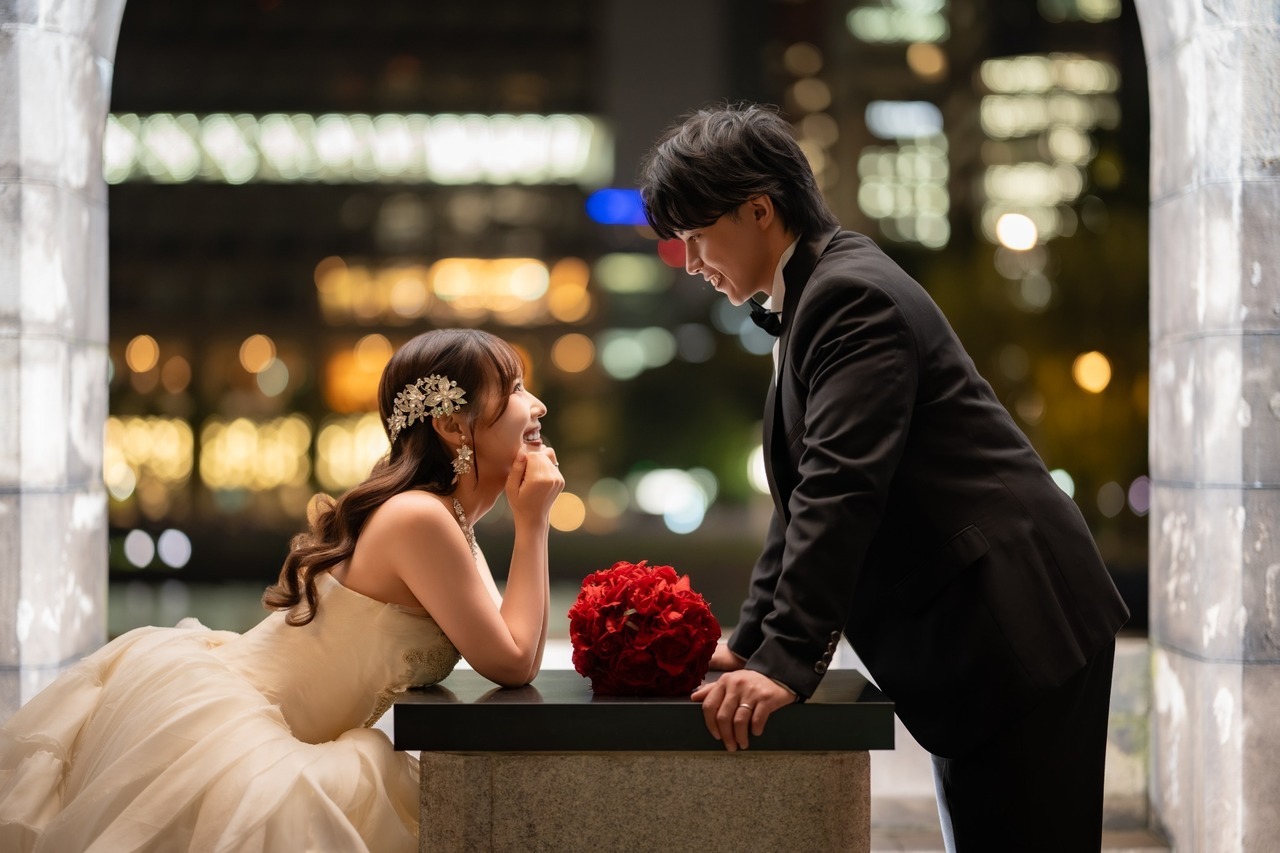 和田倉門周辺で向かい合い笑顔を見せる新郎新婦の夜のウェディング前撮り